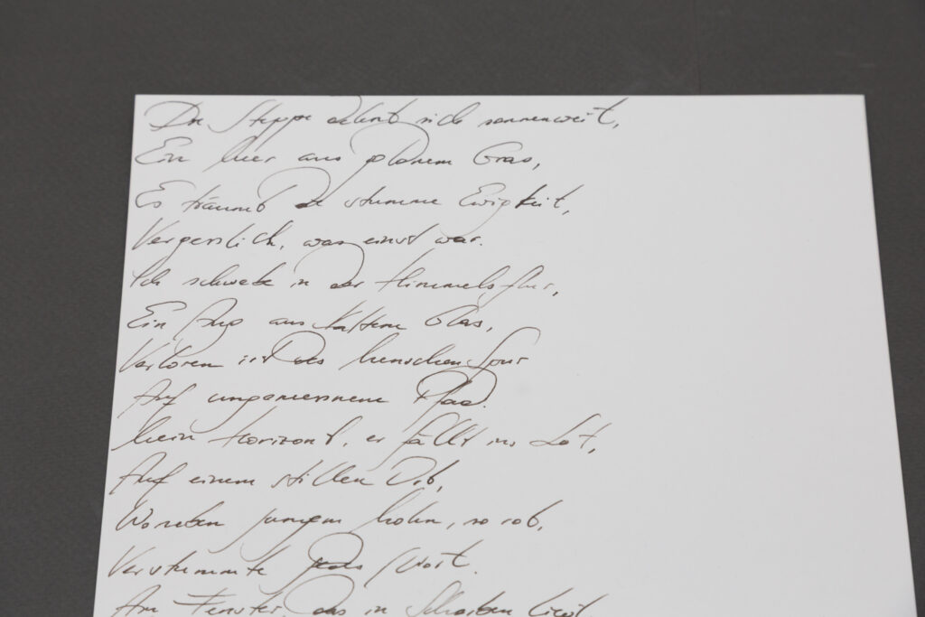Ausstellungsansicht der Ausstellung "Vertical Horizon" im Lentos Kunstmuseum Linz, im Rahmen der Kyiv Biennale 2025. Zu sehen ist die Arbeit "wie eine Geranie rot" der aus der Ukraine stammenden bildenden Künstlerin Elena Kristofor. Aine Vitrine mit Drohnen-Gedichten verfasst von KI, geschrieben mit Feder und Tinte von Elena Kristofor.